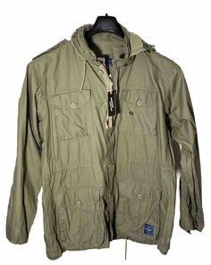 Get ready to conquer the outdoors with this Military Jacket from ROAKE. Made from durable cotton, this mid-length coat features a full zip and button closure, hideaway hood, and multiple pockets for all your essentials. The solid green color and army/outdoor theme make it perfect for summer, fall, or spring walks. Suitable for travel, casual wear, or work, this regular-fit jacket is designed to provide both comfort and style. It comes in size L and has accents of buttons and zippers that add to its overall charm. So gear up and step out in style with this ROAKE Men's Cotton Fatigue Utility Jacket, now with tags! Solid Green, Workout Jacket, Utility Jacket, The Outdoors, Summer Fall, Mid Length, Green Color, Vest Jacket, Military Jacket