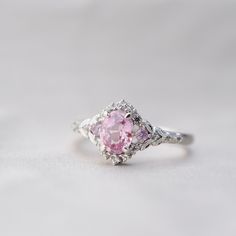 "Pink sapphire boho engagement ring in white gold with diamonds. Vintage inspired fantasy engagement ring. This engagement ring features an oval peach pink sapphire. The sapphire in unheated, sparkling and clean. It is set in Enchanted Forest setting, 14k Rose Gold, 12 white diamonds and 2 matching pink sapphires on the sides. This ring would make a beautiful unique engagement ring or promise ring as well as anniversary gift. It comes in a gorgeous rose wood ring box, ready to present. We offer Pink Promise Rings For Her, White Gold Pink Sapphire Ring, Silver Pink Sapphire Ring, Dreamy Rings, Pink Wedding Ring, Sapphire Ring Engagement, Peach Sapphire Rings, Pink Sapphire Engagement Ring, Boho Engagement Ring