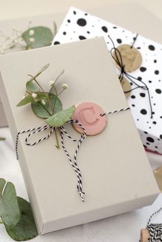 a gift wrapped in white paper with a pink ribbon