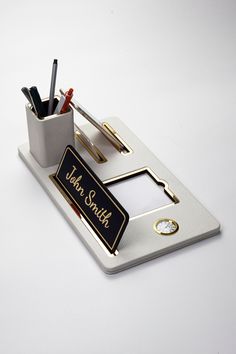 a pen holder with pens and pencils in it on a white surface, next to a pair of scissors