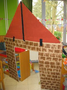 a cardboard house made to look like a brick building with a red roof and chimney