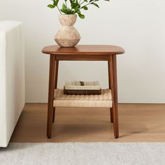 a wooden table with a book on it next to a white couch and potted plant