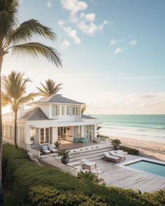 a large white house sitting on top of a lush green hillside next to the ocean