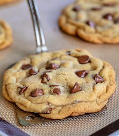 chocolate chip cookies sitting on top of a cookie sheet with a spoon in the middle