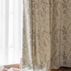 a teddy bear sitting on the floor next to a window with white curtains in it