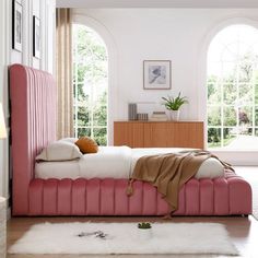 a pink bed sitting in the middle of a living room next to a white rug