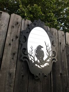 a mirror that is on the side of a wooden fence with trees in the background