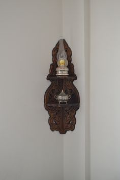 an ornate wooden clock mounted to the side of a wall with a light on it