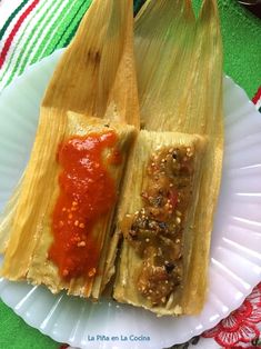 two tamales are sitting on a paper plate with sauce in each one, and the other half is empty