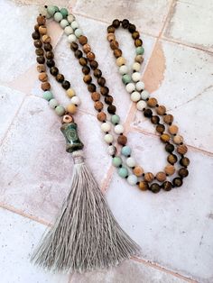 This beautiful Mala Necklace is made with 108 beads of Amazonite, Tiger's Eye, and Picture Jasper, each with its own unique healing properties. The Accent Dzi beads are believed to have protective and healing properties. This Mala necklace is not only a stunning accessory but also a tool for meditation and mindfulness. The necklace is hand-knotted between each bead and finished with a tassel under the Dzi beads.Materials & style:- 108 beads for traditional Mala use- Dzi beads for spiritual signi Spiritual Amazonite 8mm Beads Jewelry, Spiritual Amazonite Jewelry With 8mm Beads, Amazonite Crystal Necklace With Round Beads, Amazonite Crystal Necklace With Round Natural Stones, Spiritual Round Beads Crystal Necklaces For Layering, Spiritual Crystal Necklaces With Round Beads For Layering, Beaded Mala Amulet For Meditation, Beaded Amulet Mala For Meditation, Spiritual Round Beads Necklaces For Layering