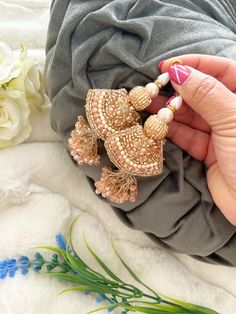 a person holding some kind of brooch in their hand next to flowers and cloth