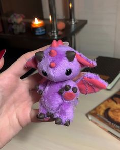 a hand holding a small purple stuffed animal