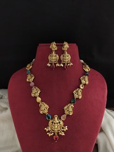 Introducing our Simple Antique Navratna Necklace Set, a timeless piece featuring elegant Lakshmi and peacock motifs. Adorned with vibrant Navratna stones, this exquisite necklace is complemented by matching peacock-studded Lakshmi earrings. The set is finished with delicate pearl and golden ball drops, adding a touch of sophistication and grace to any traditional attire. Perfect for festive occasions and cultural celebrations. Care Instructions: Handle with care to maintain its antique allure. Avoid contact with water, perfumes, and chemicals. Store in a dry, air-tight container when not in use. Disclaimer: Minor variations may occur due to differences in screen resolution and lighting. Contact Information: For inquiries or additional jewelry requirements, contact us on WhatsApp at +91 967 Peacock Design Necklaces For Puja And Diwali, Temple Jewelry Kundan Necklace With Peacock Design For Celebrations, Festive Temple Necklace With Peacock Design For Navratri, Festive Navratri Temple Necklace With Peacock Design, Bollywood Temple Necklace With Peacock Design For Diwali, Elegant Temple Necklace With Peacock Design For Navratri, Multicolor Temple Necklace With Peacock Design For Celebration, Peacock Design Necklace For Puja And Navratri, Temple Necklace With Peacock Design For Festivals And Celebrations