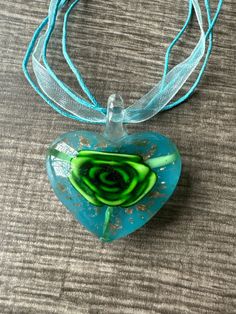 This necklace is made with a glass Lampwork heart and the flower is green, gold accents and a blue background. Note: Colors may vary depending on your monitor  I do have other colors for the necklace strands for both multi and single strand.  If you are looking for a different variation, feel free to touch base with me and I can let you know if I have what you are looking for. Shipping Info: All orders are shipped from Canada and they are sent through Canada Post.  If you would like expedited/fa Blue Glass Heart Beads Jewelry, Blue Glass Jewelry With Heart Beads, Glass Heart Pendant Necklace For Gift, Glass Heart Beads Necklace As A Gift, Heart-shaped Glass Necklaces For Jewelry Making, Glass Necklaces With Heart Beads For Gifts, Turquoise Flower Necklaces For Gift, Turquoise Glass Jewelry For Gift, Green Flower-shaped Glass Jewelry