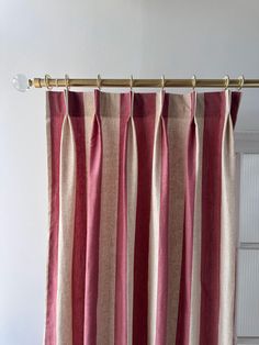 red and beige striped curtains hanging on a curtain rod in front of a white wall