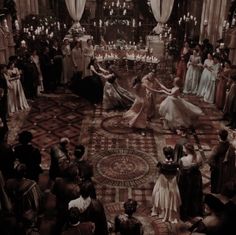 several people in formal dress are dancing on the floor with candles lit up behind them