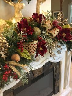 a fireplace mantel decorated for christmas with red flowers and greenery on the mantle