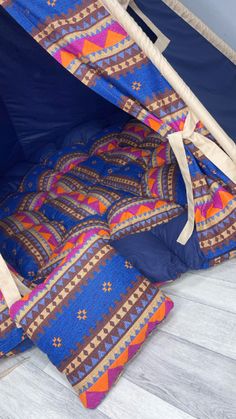 the inside of a tent that is blue and has colorful patterns on it, with two pillows