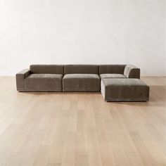 an l - shaped sectional sofa on a hardwood floor in front of a white wall