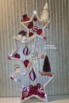 a christmas tree made out of star shaped ornaments with lights and decorations on it, sitting in front of a striped wall