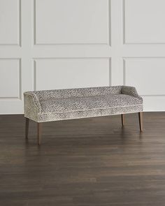 a leopard print bench sitting on top of a hard wood floor next to a white wall