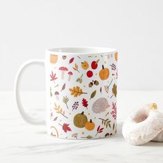 an autumn themed coffee mug next to a donut