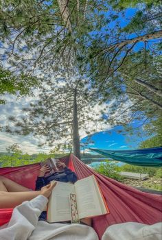 a person laying in a hammock reading a book