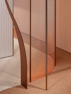 a curved metal object on the ground in a room with pink walls and carpeting