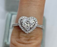 a woman's hand with a heart shaped diamond ring on top of her finger