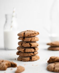 a stack of chocolate cookies next to a glass of milk on a white countertop