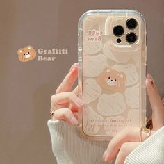 a woman holding up her phone case with an image of a teddy bear on it