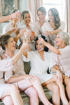 a group of women sitting on top of a couch holding wine glasses in their hands