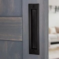 an open door with a black handle in front of a living room and kitchen area