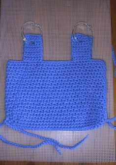 a blue crocheted bag with two handles on a mat that has been stitched together