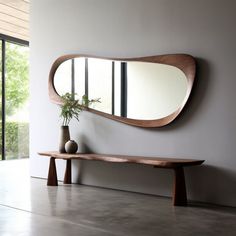 a wooden bench sitting under a large mirror next to a vase with a plant on it