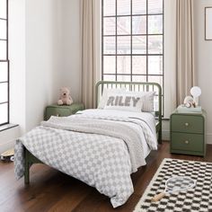 a child's bedroom with white walls and wood floors, green bed frame, black and white checkered rug