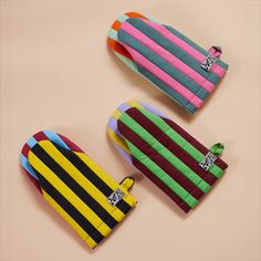 three colorful striped wallets sitting on top of a table next to each other and one has a tag in the middle