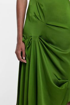 a woman in a green dress with her hands on her hip and the bottom half of her skirt