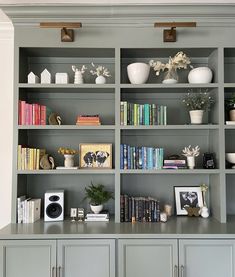 a bookshelf filled with lots of books and vases on top of it