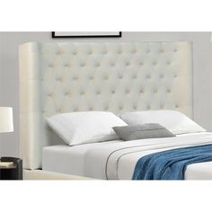 a bed with white linens and pillows on it, next to a night stand