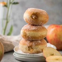 a stack of doughnuts sitting on top of a plate next to an apple