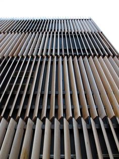 a tall building with wooden slats on it's sides and sky in the background