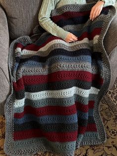 a woman sitting on a couch under a blanket