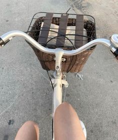 a person riding a bike with a basket on the front wheel and one foot propped up against the handlebars