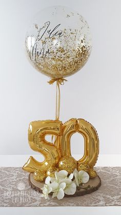 a golden balloon with the number 50 on it and some flowers in front of it