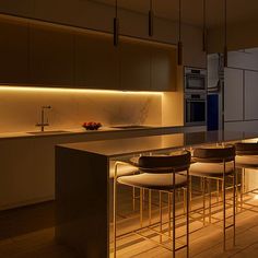 a modern kitchen with bar stools and lights on the countertop, along with an island