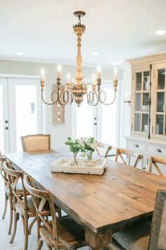 a dining room table with chairs and a tray on it's centerpiece in front of a doorway