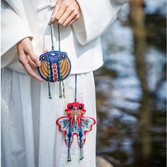 a woman in white dress holding an ornament shaped like a butterfly with beads