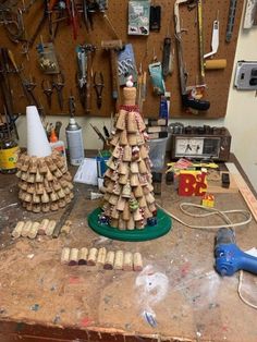 a wooden christmas tree sitting on top of a workbench with tools hanging from the wall