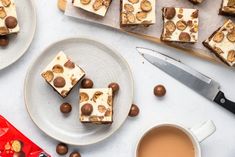 some desserts are sitting on plates next to a cup of coffee and a knife